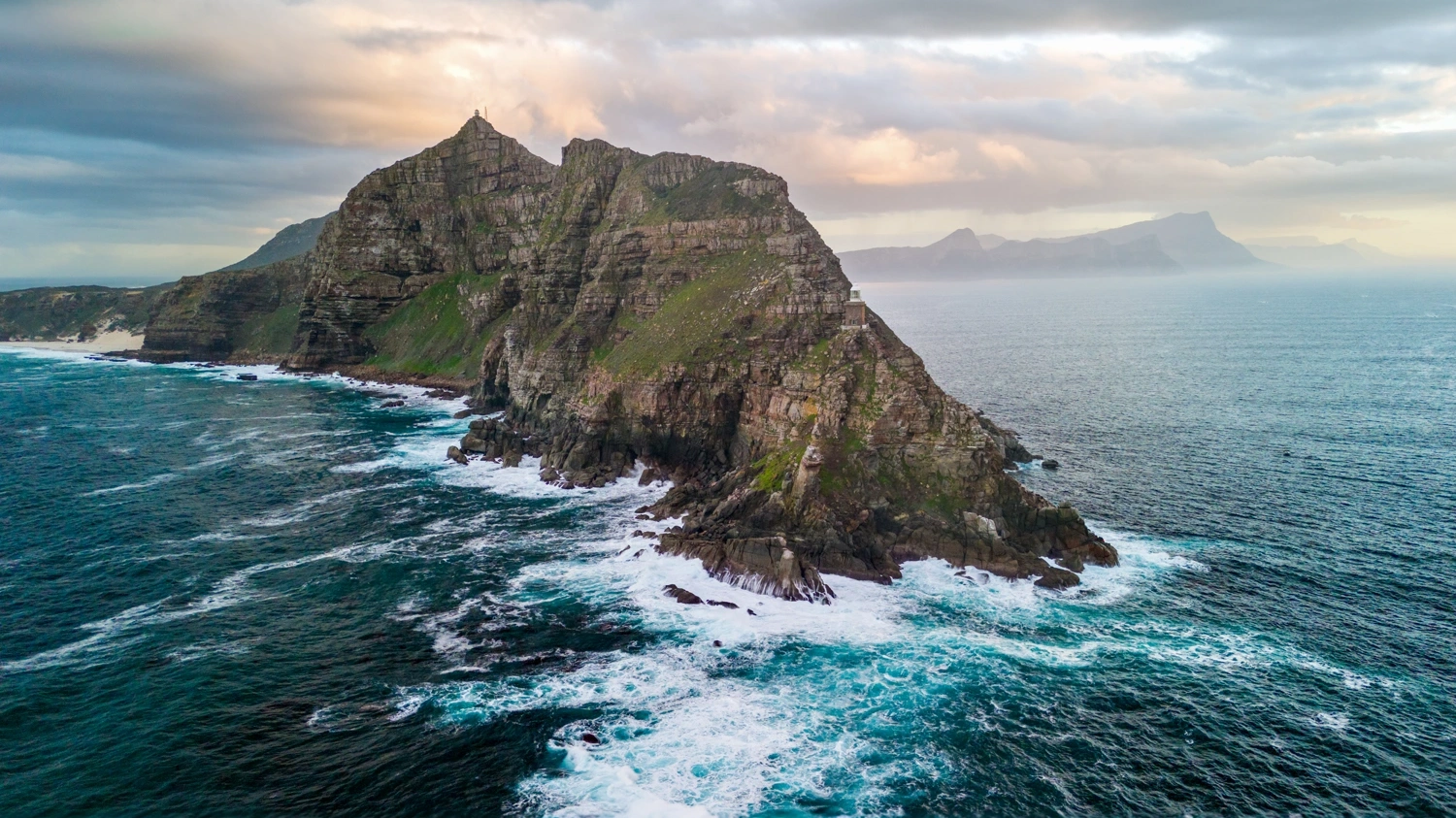 Cape Point lighthouse perched on dramatic coastal cliffs with crashing waves below
