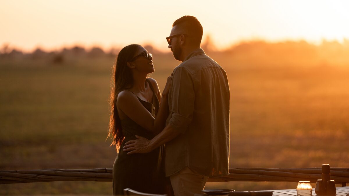 Romantic couple watching African sunset from a luxury safari lodge